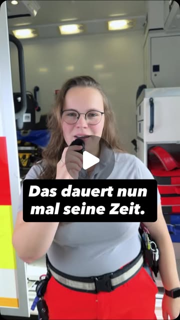 Rettungskraft erklärt vor einem Einsatzfahrzeug den Ablauf nach einem Notruf
